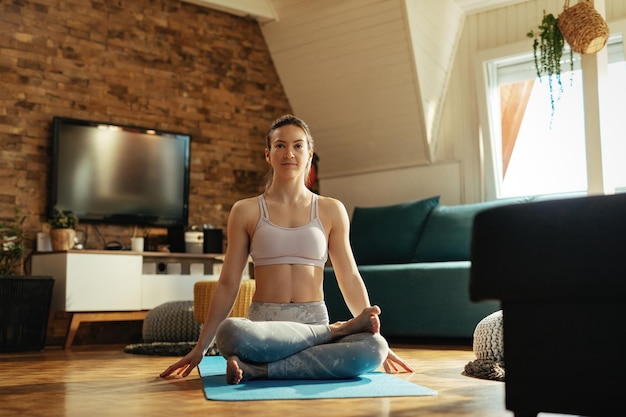 Athletische Frau, die Yoga-Meditationsübungen macht, während sie zu Hause übt.