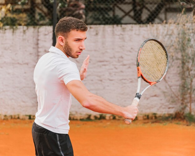 Athletischer Junge, der Tennis spielt