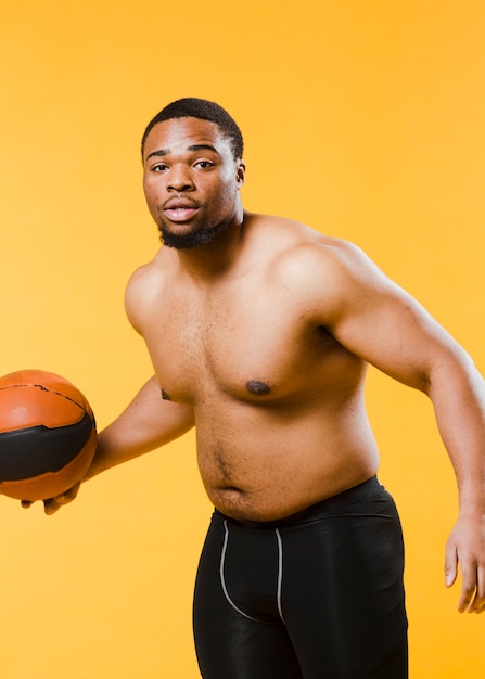 Athletischer Mann, der den Basketball hemdlos spielt