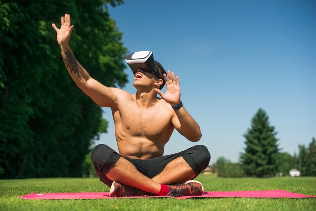 Athletischer Mann, der die Gläser einer virtuellen Realität im Freien verwendet