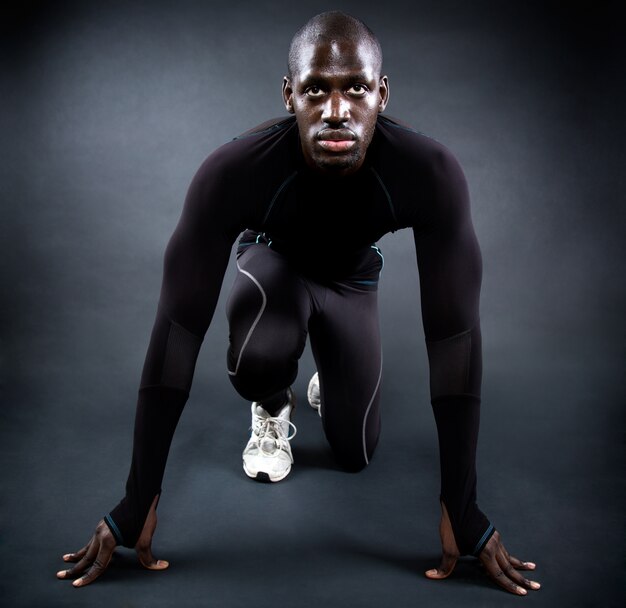 Athletischer Mann läuft in schwarzem Hintergrund.