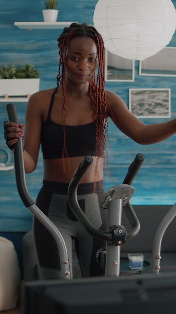 Athletisches Training der schwarzen Frau auf elliptischem Fahrrad, das Cardio-Sport praktiziert