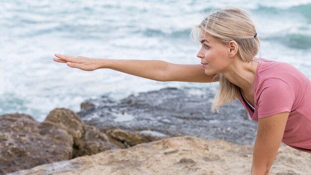 Attraktive blonde Frau, die Yoga im Freien tut