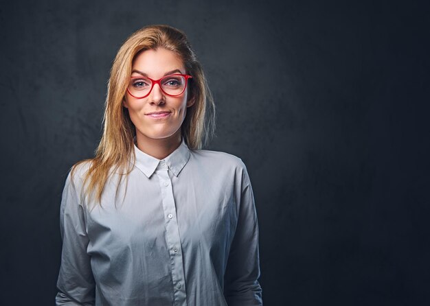 Attraktive blonde Geschäftsfrau in einem weißen Hemd über grauem Hintergrund.