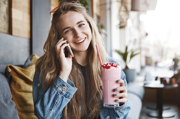 Attraktive blonde Studentin in der Jeansjacke, die h kippt