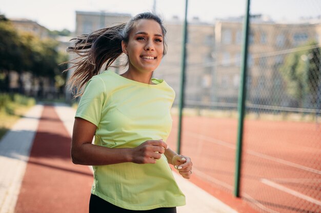 Attraktive Brünette in Bewegung beim Joggen auf dem Sportplatz