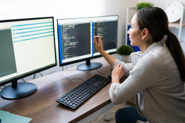 Attraktive Frau, die an einer Programmiersoftware-App arbeitet. Junge Frau, die ihre Arbeit am Computer kodiert und überprüft