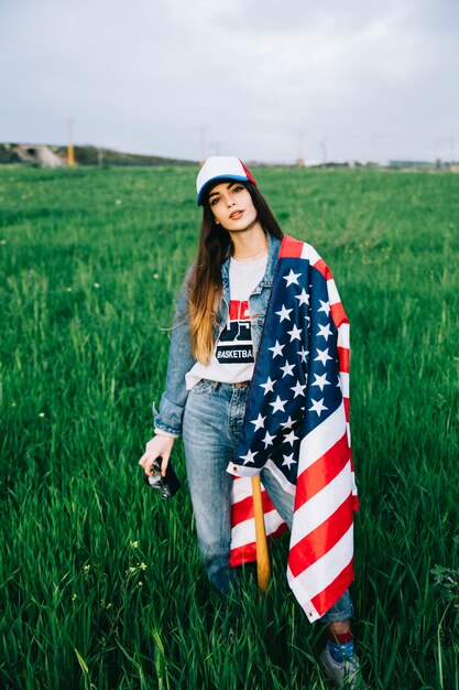 Attraktive Frau, die auf dem Gebiet mit amerikanischer Flagge bleibt