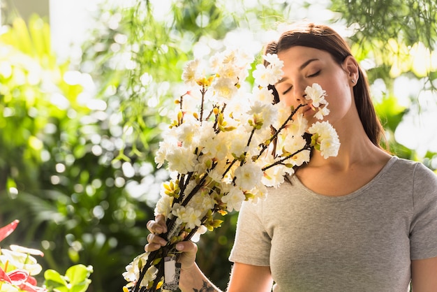 Attraktive Frau, die Bündel Blumenzweige nahe Gesicht hält