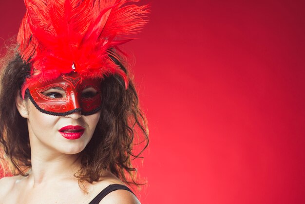 Attraktive Frau, die in der roten Maske aufwirft