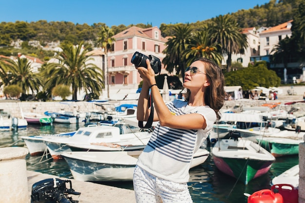 Attraktive Frau im Urlaub in Europa am Meer auf einer Kreuzfahrt, die Fotos vor der Kamera macht