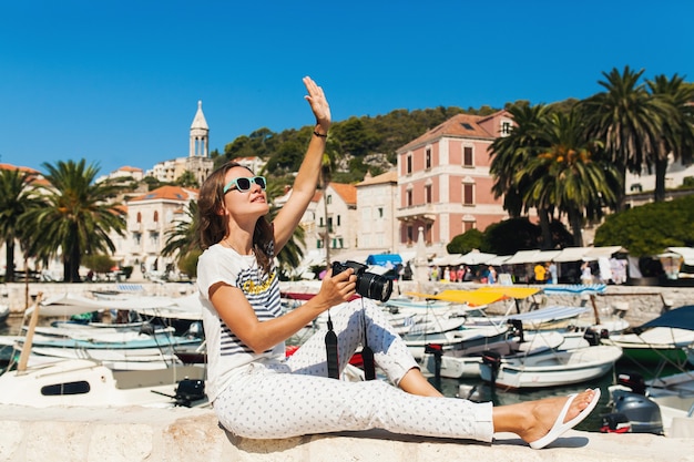 Attraktive Frau im Urlaub in Europa am Meer auf einer Kreuzfahrt, die Fotos vor der Kamera macht