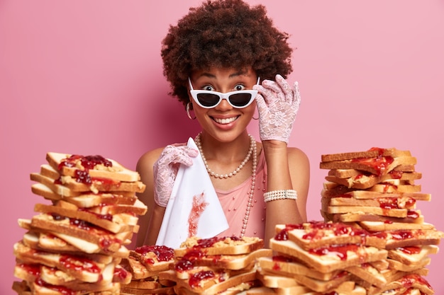 Attraktive frau mit afro-haaren, umgeben von erdnussbutter-gelee-sandwiches