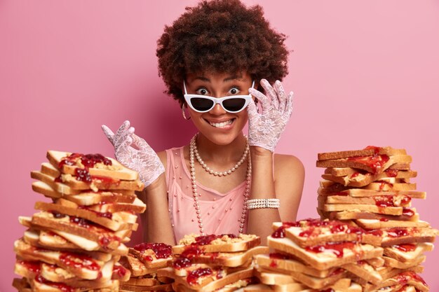 Attraktive Frau mit Afro-Haaren, umgeben von Erdnussbutter-Gelee-Sandwiches