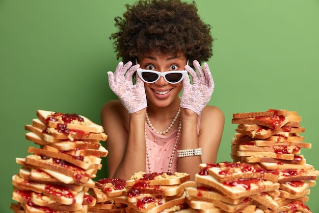 Attraktive Frau mit Afro-Haaren, umgeben von Erdnussbutter-Gelee-Sandwiches