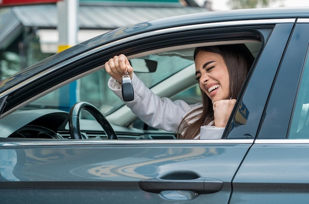 Attraktive Frau posiert hinter dem Steuer ihres Autos
