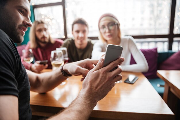 Attraktive Freunde, die im Café sitzen und Telefon betrachten.