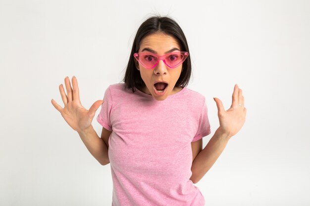 Attraktive glückliche lustige lustige überraschte emotionale Frau im rosa T-Shirt isolierte Arme vorwärts überraschten schockierten Gesichtsausdruck