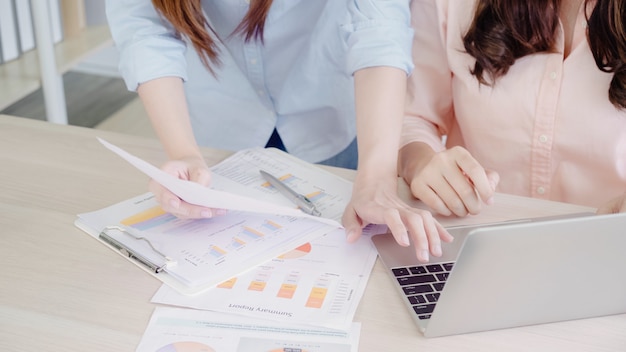 Attraktive intelligente kreative asiatische Geschäftsfrauen in der intelligenten Freizeitkleidung, die an Laptop beim Sitzen arbeitet