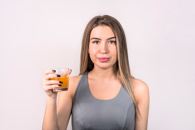 Attraktive junge Dame in der Sportkleidung mit Glas Getränk