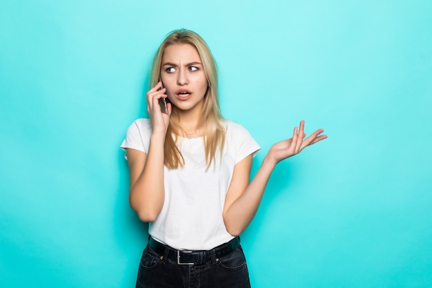 Attraktive junge Frau, die am Telefon gegen grüne Wand spricht