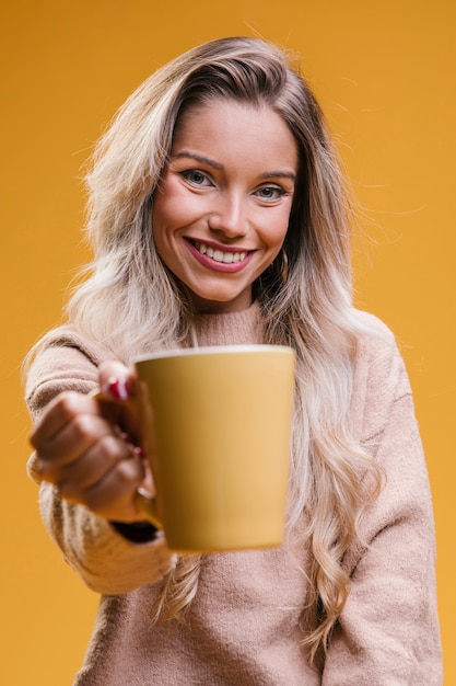 Attraktive junge Frau, die den Tasse Kaffee betrachtet Kamera zeigt