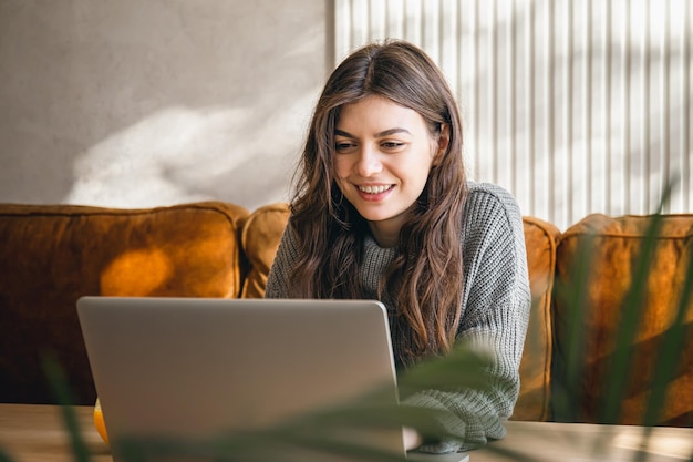 Attraktive junge Frau, die früh morgens an einem Laptop arbeitet