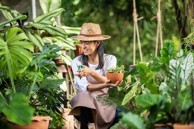 Attraktive junge Frau, die mit Zierpflanzen im Gartencenter arbeitet. weibliche Vorgesetzte, die Pflanzen im Garten draußen in der Sommernatur untersucht Schönes Gärtnerlächeln. Pflanzenpflege.