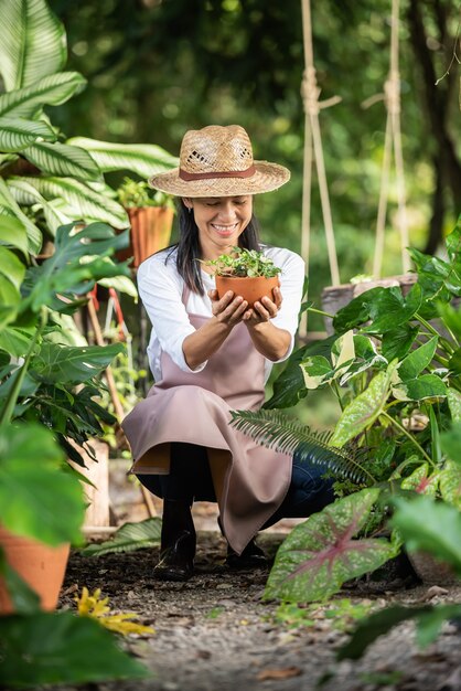 Attraktive junge Frau, die mit Zierpflanzen im Gartencenter arbeitet. weibliche Vorgesetzte, die Pflanzen im Garten draußen in der Sommernatur untersucht Schönes Gärtnerlächeln. Pflanzenpflege.