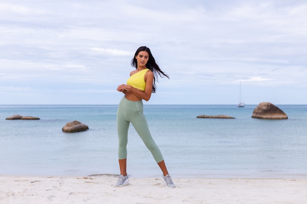 Attraktive junge Frau in der bunten Sportkleidung am Strand