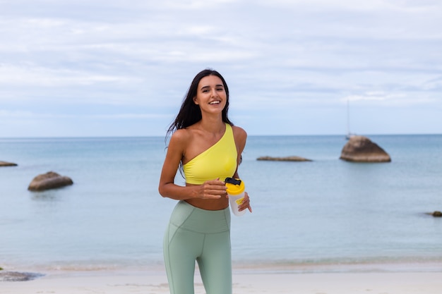 Attraktive junge Frau in der bunten Sportkleidung am Strand