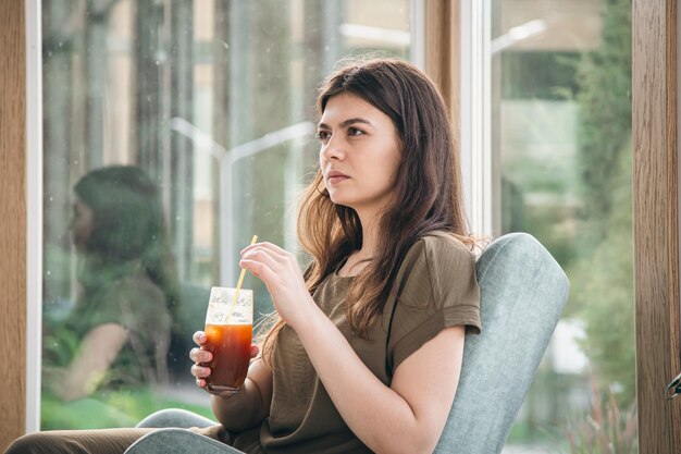 Attraktive junge Frau mit Espresso-Stärkungsmittel im Café-Interieur