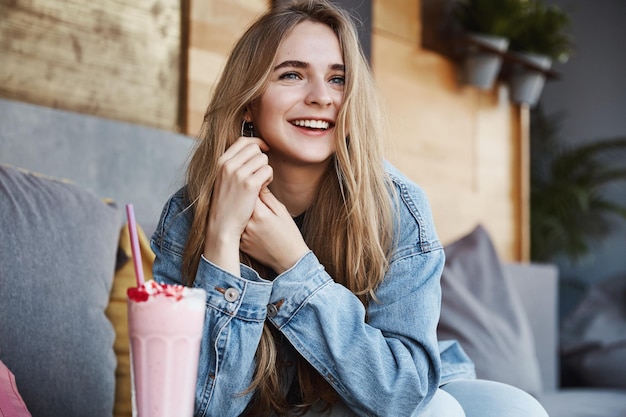 Attraktive junge Frau trinkt Smoothie im Café und schaut hinaus