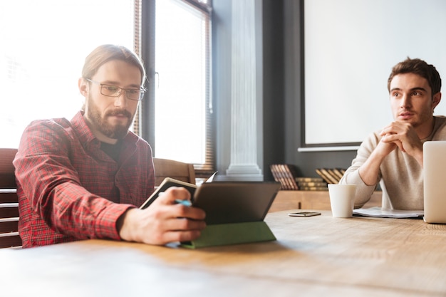 Attraktive junge Kollegen, die im Büro sitzen