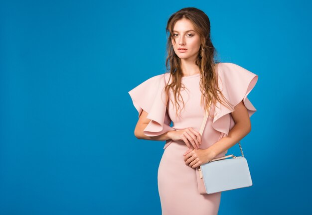 Attraktive junge stilvolle sexy Frau im rosa Luxuskleid, Sommermodetrend, schicker Stil, hält trendige Handtasche