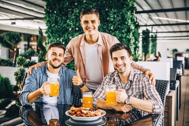 Attraktive Jungs trinken Bier im Café auf der Sommerterrasse