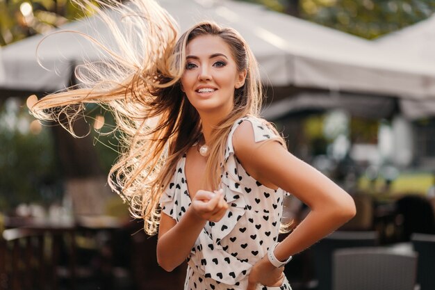 Attraktive lächelnde Frau mit langen Haaren, die Spaß am sonnigen Sommertag glücklich haben