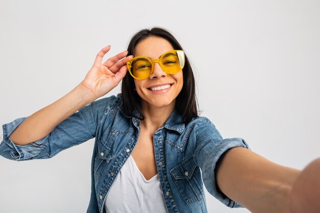 Attraktive lächelnde glückliche Frau, die selfie Foto lokalisiert auf weißem Studio macht