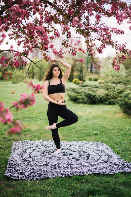 Attraktive moderne Frau, die Yogapraxis im Garten tut
