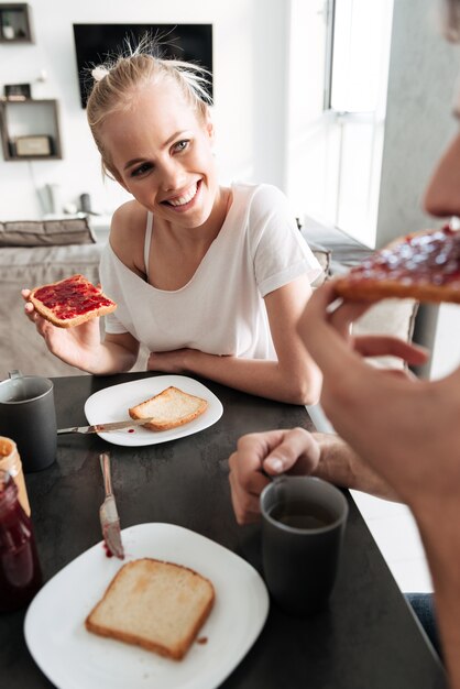 Attraktive nette Frau, die ihren Mann betrachtet, während sie Frühstück essen