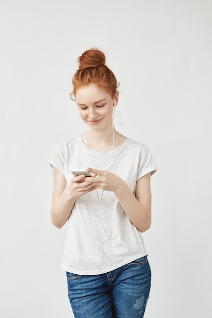 Attraktive rothaarige Frau mit Sommersprossen lächelnd, die Telefon betrachten.