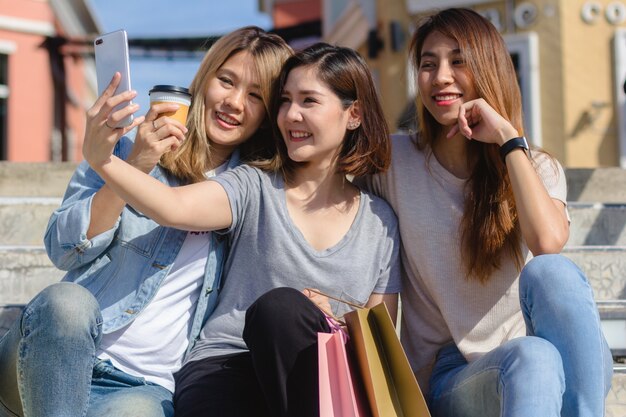 Attraktive schöne asiatische Frau, die einen Smartphone beim Einkauf in der Stadt verwendet