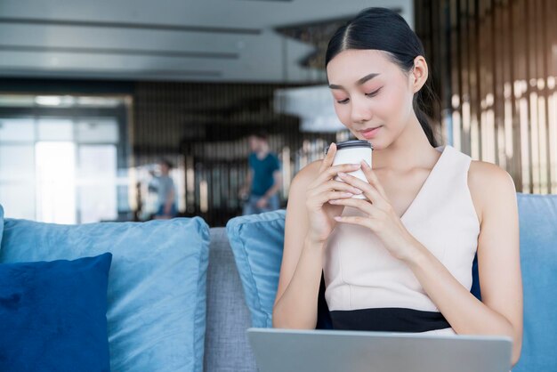 Attraktive schöne asiatische frau smart casual entspannen genießen sie die arbeit von zu hause aus socail distanzierung der quarantäne auf dem sofa asiatische weibliche glück mit privatem moment arbeiten auf dem sofa zu hause hintergrund