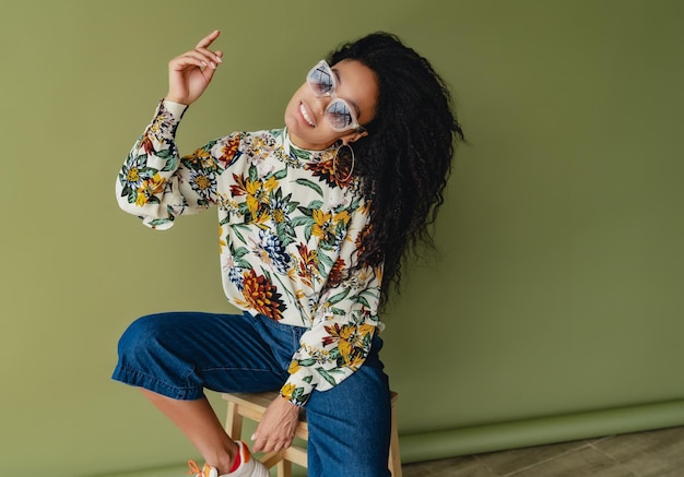 Attraktive schwarze Afroamerikanerin in stylischem Outfit auf grünem Studiohintergrund