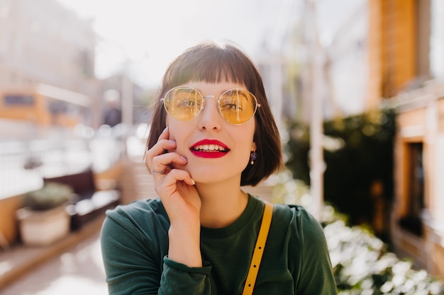 Attraktive sinnliche Frau in gelber Sonnenbrille, die Interesse ausdrückt. Schönes weißes Mädchen, das im Frühlingstag entspannt.