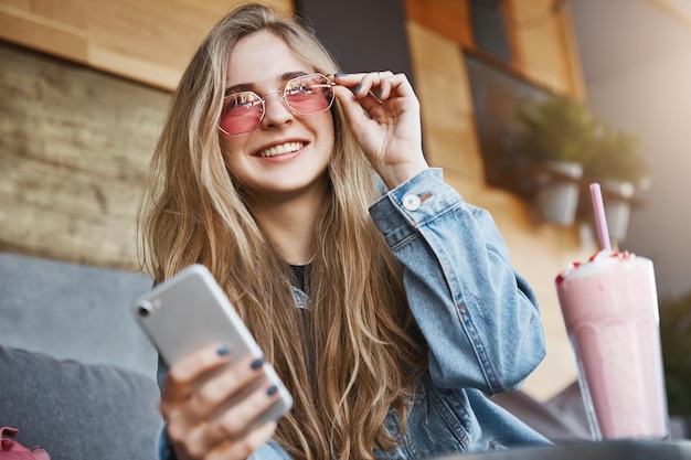 Attraktive und fröhliche kaukasische blonde Frau mit trendiger Sonnenbrille