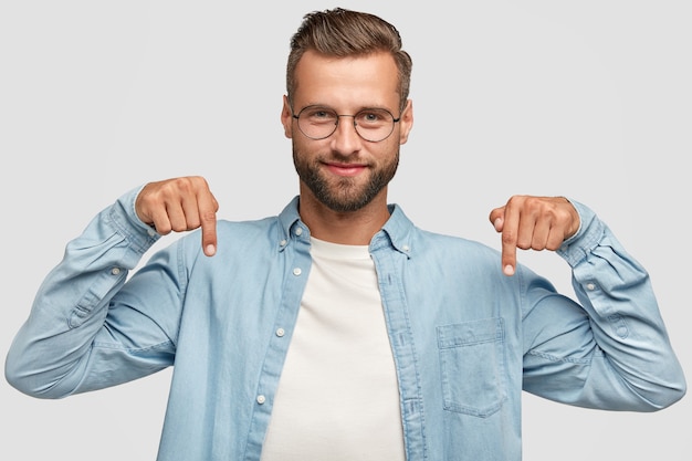 Kostenloses Foto attraktiver bärtiger kerl, der gegen die weiße wand aufwirft