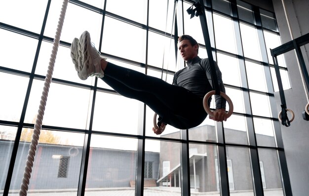 Attraktiver fitter Mann, der drinnen im Fitnessstudio trainiert