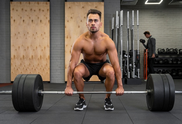 Attraktiver fitter Mann, der drinnen mit Gewichten trainiert