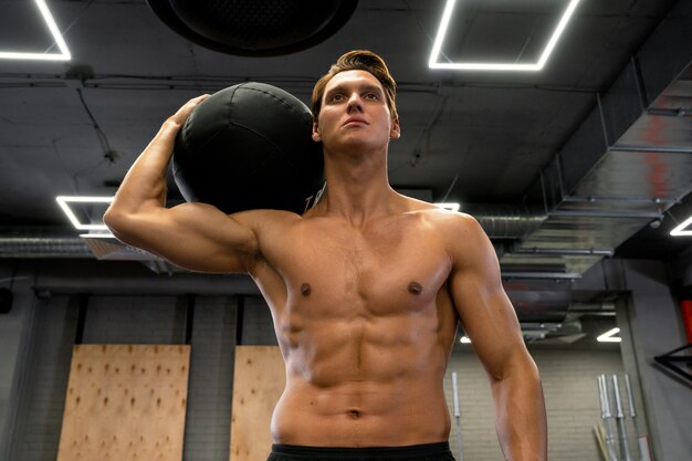 Attraktiver fitter Mann, der drinnen mit Gymnastikball trainiert